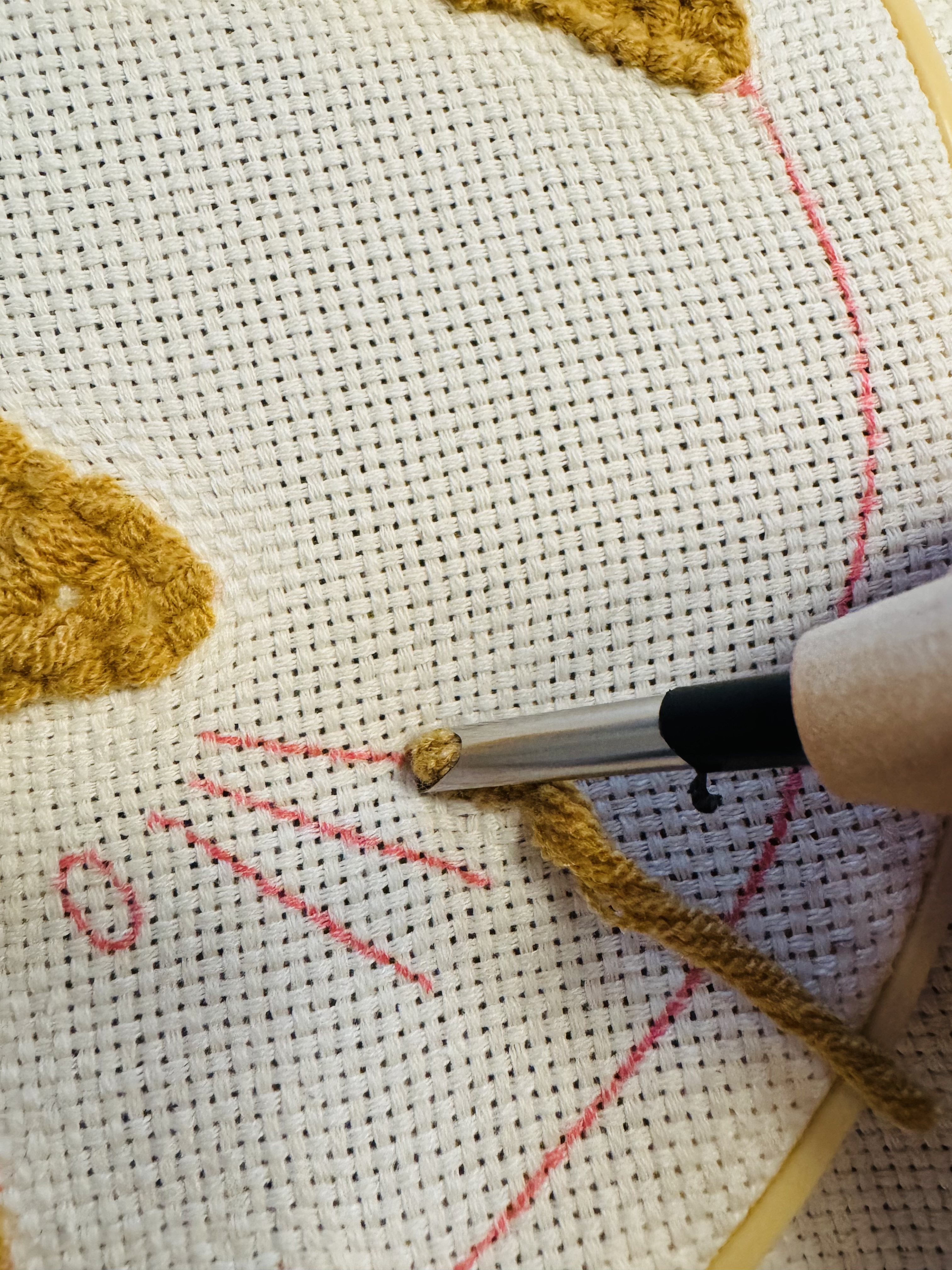 Close up hoe je de naald goed in het canvas steekt